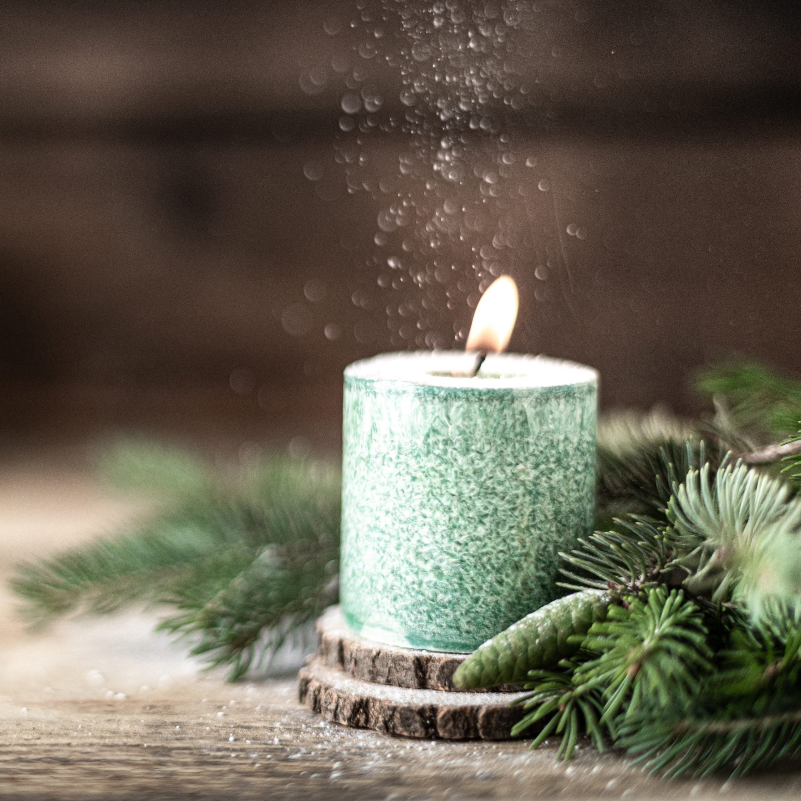Christmas green candle with fir branches and cones on wooden table